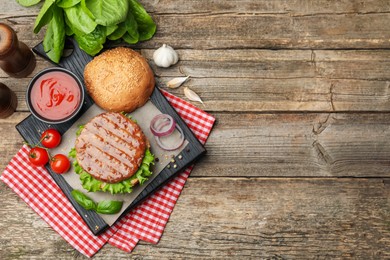 Photo of Delicious hamburger patty, bun, vegetables and spices on wooden table, flat lay. Space for text