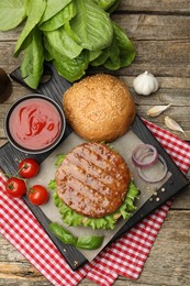 Photo of Delicious hamburger patty, bun, vegetables and spices on wooden table, flat lay