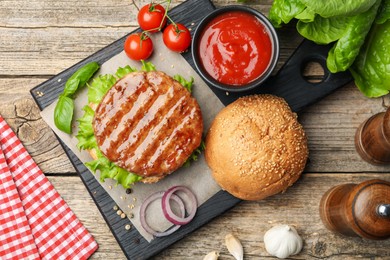 Photo of Delicious hamburger patty, bun, vegetables and spices on wooden table, flat lay