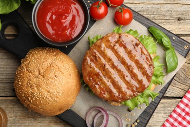 Photo of Delicious hamburger patty, bun, vegetables and spices on wooden table, flat lay