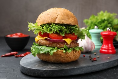 Photo of Delicious hamburger with patty served on black table, closeup