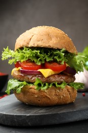Photo of Delicious hamburger with patty served on black table, closeup