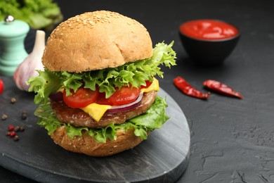 Photo of Delicious hamburger with patty served on black table, closeup. Space for text