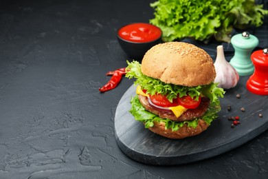 Photo of Delicious hamburger with patty served on black table. Space for text
