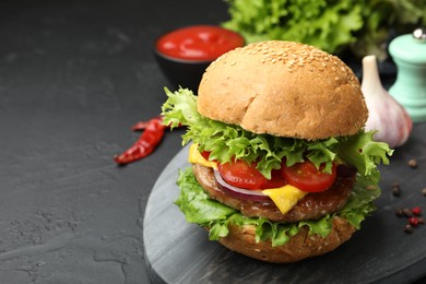 Photo of Delicious hamburger with patty served on black table, closeup. Space for text