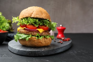Photo of Delicious hamburger with patty served on black table, closeup. Space for text