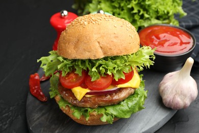 Photo of Delicious hamburger with patty served on black table, closeup