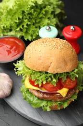 Photo of Delicious hamburger with patty served on black table, closeup