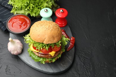Photo of Delicious hamburger with patty served on black table. Space for text