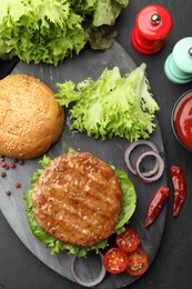Photo of Delicious hamburger with patty served on black table, flat lay