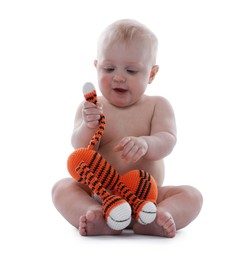 Photo of Cute little baby with knitted toy tiger on white background