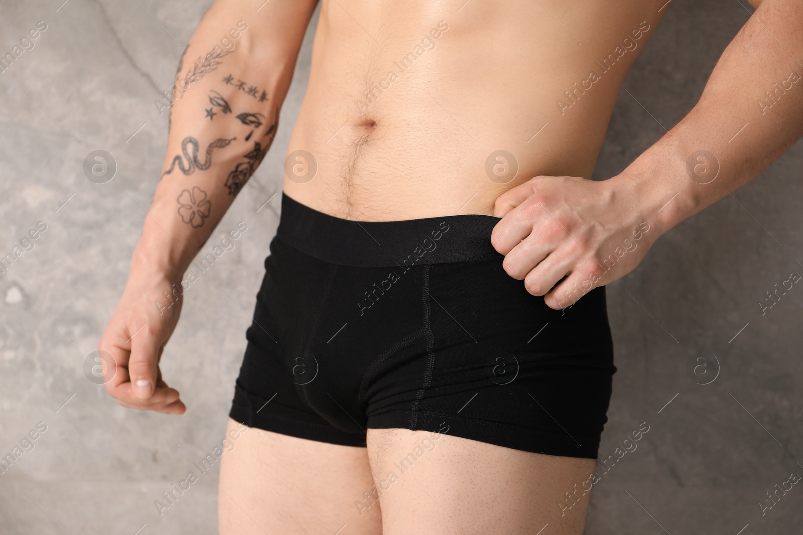 Young man in stylish black underwear near grey wall indoors, closeup Photo of Young man in stylish black underwear near grey wall indoors, closeup