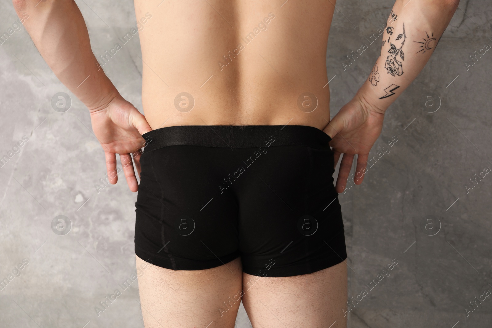 Young man in stylish black underwear near grey wall indoors, closeup Photo of Young man in stylish black underwear near grey wall indoors, closeup
