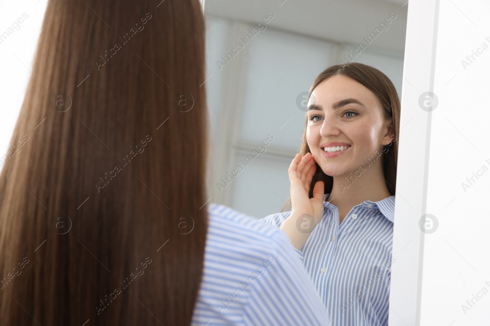 Beautiful woman looking at herself in mirror indoors Photo of Beautiful woman looking at herself in mirror indoors