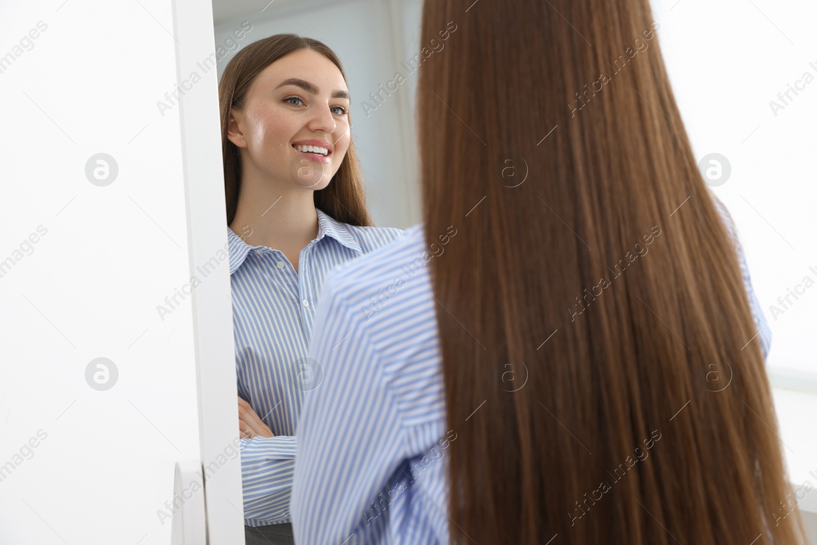 Photo of Beautiful woman looking at herself in mirror indoors