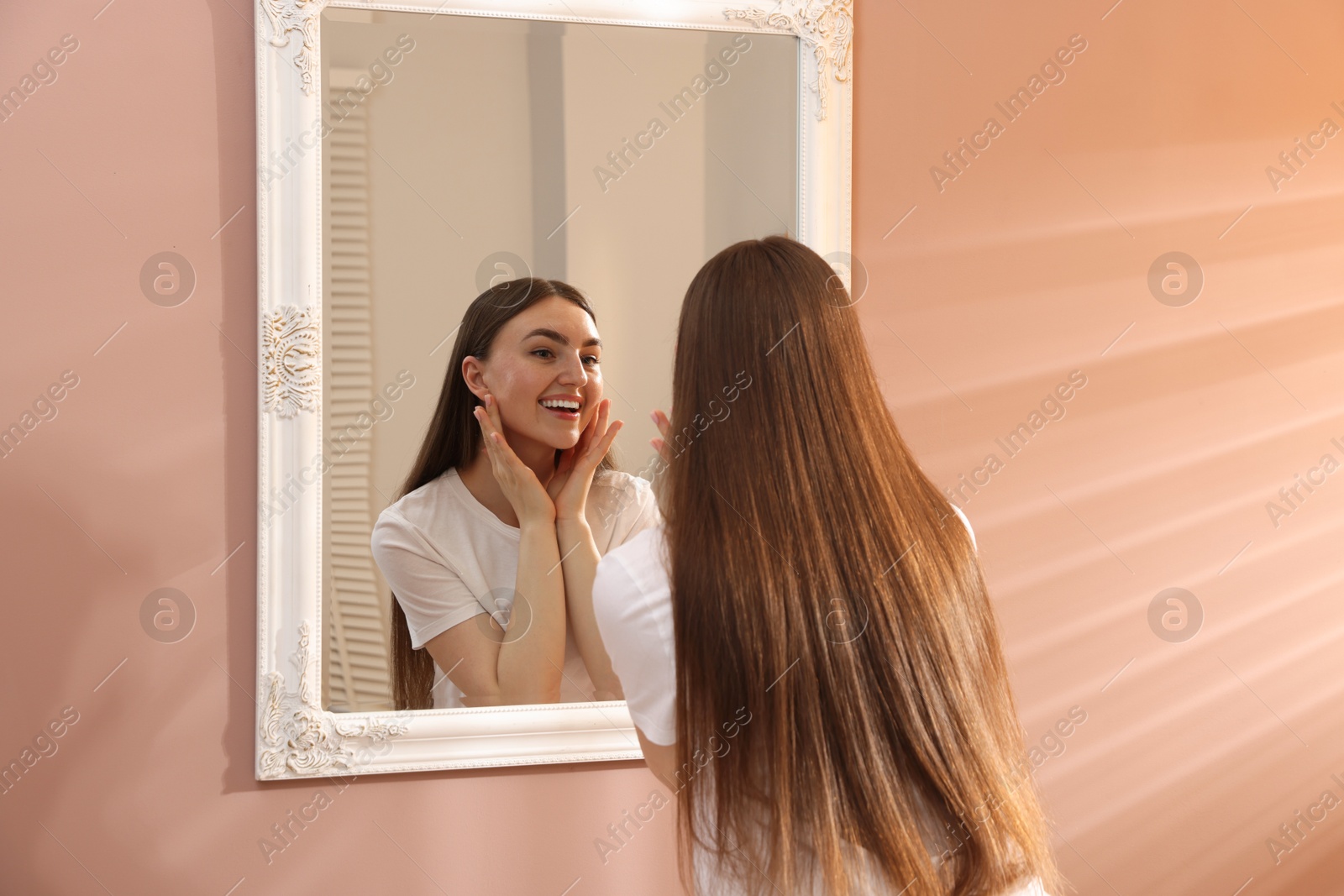 Beautiful woman looking at herself in mirror indoors Photo of Beautiful woman looking at herself in mirror indoors