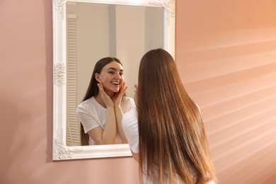 Photo of Beautiful woman looking at herself in mirror indoors