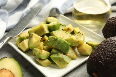 Photo of Tasty cut avocados with dressing on grey textured table, closeup