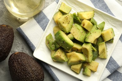 Photo of Tasty cut avocados with dressing on grey textured table, flat lay