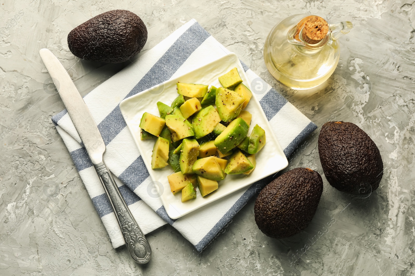 Tasty cut avocados with dressing and knife on grey textured table, flat lay Photo of Tasty cut avocados with dressing and knife on grey textured table, flat lay
