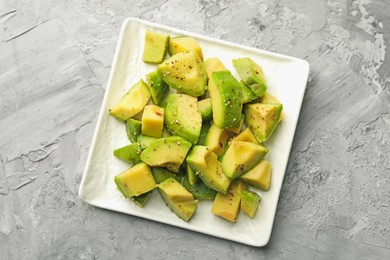 Photo of Tasty cut avocados with dressing on grey textured table, top view