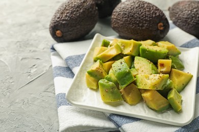Photo of Tasty cut avocados with dressing on grey textured table, closeup