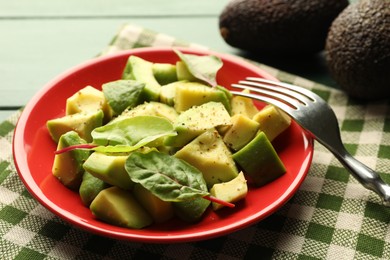 Photo of Tasty cut avocados with spinach and dressing on green wooden table, closeup