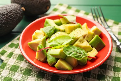 Photo of Tasty cut avocados with spinach and dressing on green wooden table, closeup