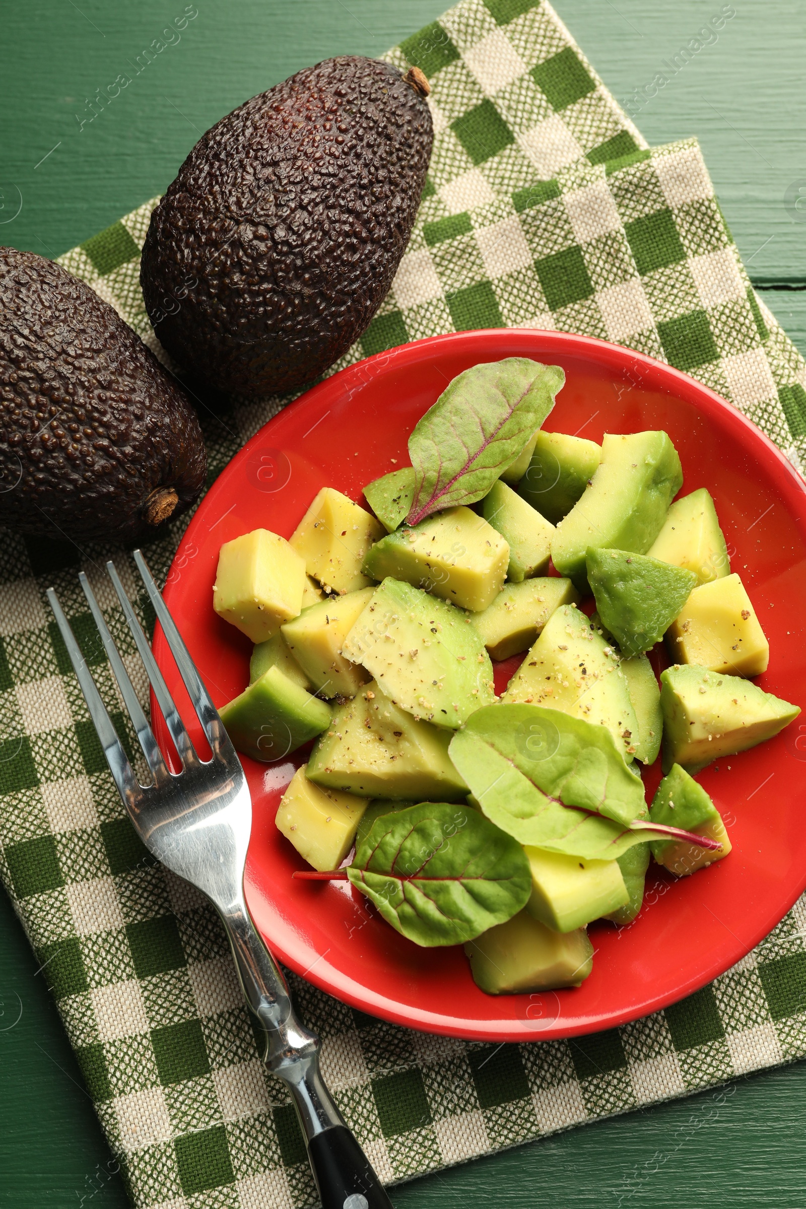 Tasty cut avocados with spinach and dressing on green wooden table, flat lay Photo of Tasty cut avocados with spinach and dressing on green wooden table, flat lay