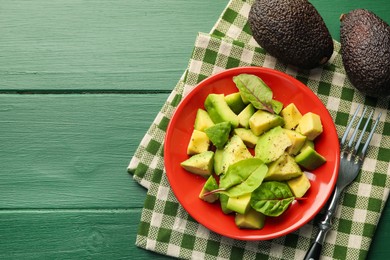 Photo of Tasty cut avocados with spinach and dressing on green wooden table, flat lay. Space for text