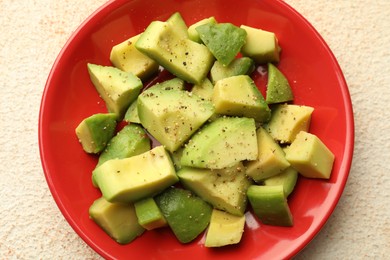 Photo of Tasty cut avocados with dressing on light textured table, top view