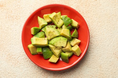 Photo of Tasty cut avocados with dressing on light textured table, top view