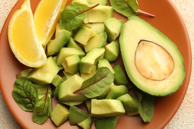 Photo of Tasty cut avocados, spinach and lemon on light textured table, top view
