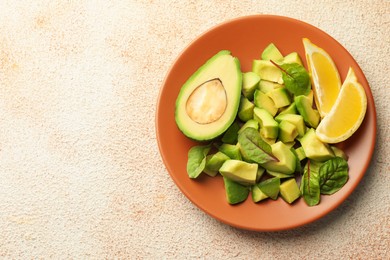 Photo of Tasty cut avocados, spinach and lemon on light textured table, top view. Space for text