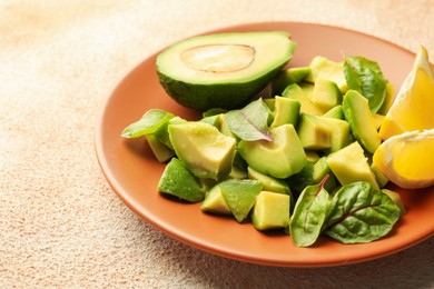 Photo of Tasty cut avocados, spinach and lemon on light textured table, closeup