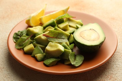 Photo of Tasty cut avocados, spinach and lemon on light textured table, closeup