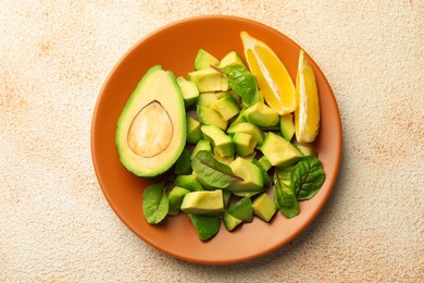 Photo of Tasty cut avocados, spinach and lemon on light textured table, top view