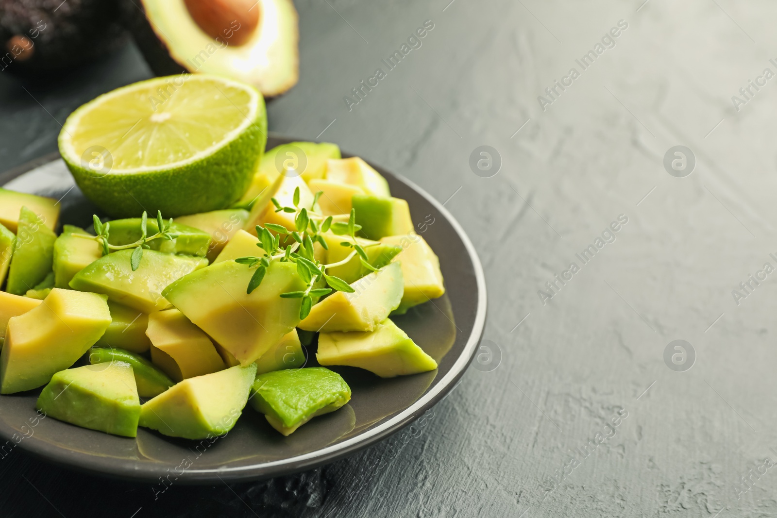 Tasty cut avocados, thyme and lime on black table, closeup. Space for text Photo of Tasty cut avocados, thyme and lime on black table, closeup. Space for text