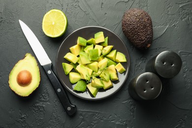 Photo of Tasty cut avocados, thyme, knife and lime on black table, flat lay