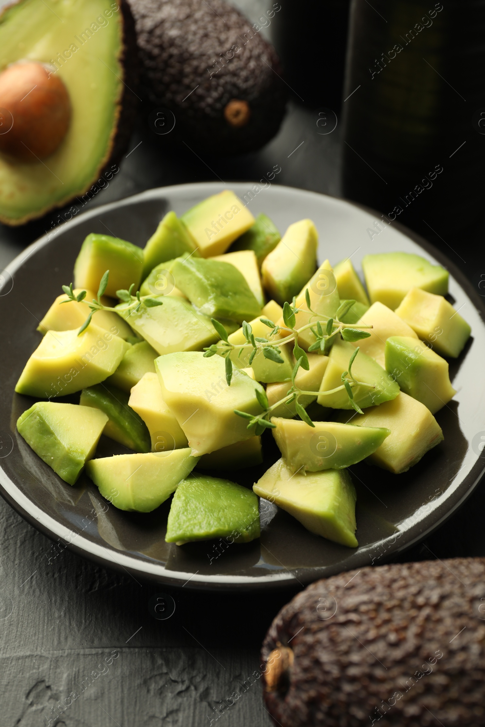 Tasty cut avocados and thyme on black table, closeup Photo of Tasty cut avocados and thyme on black table, closeup