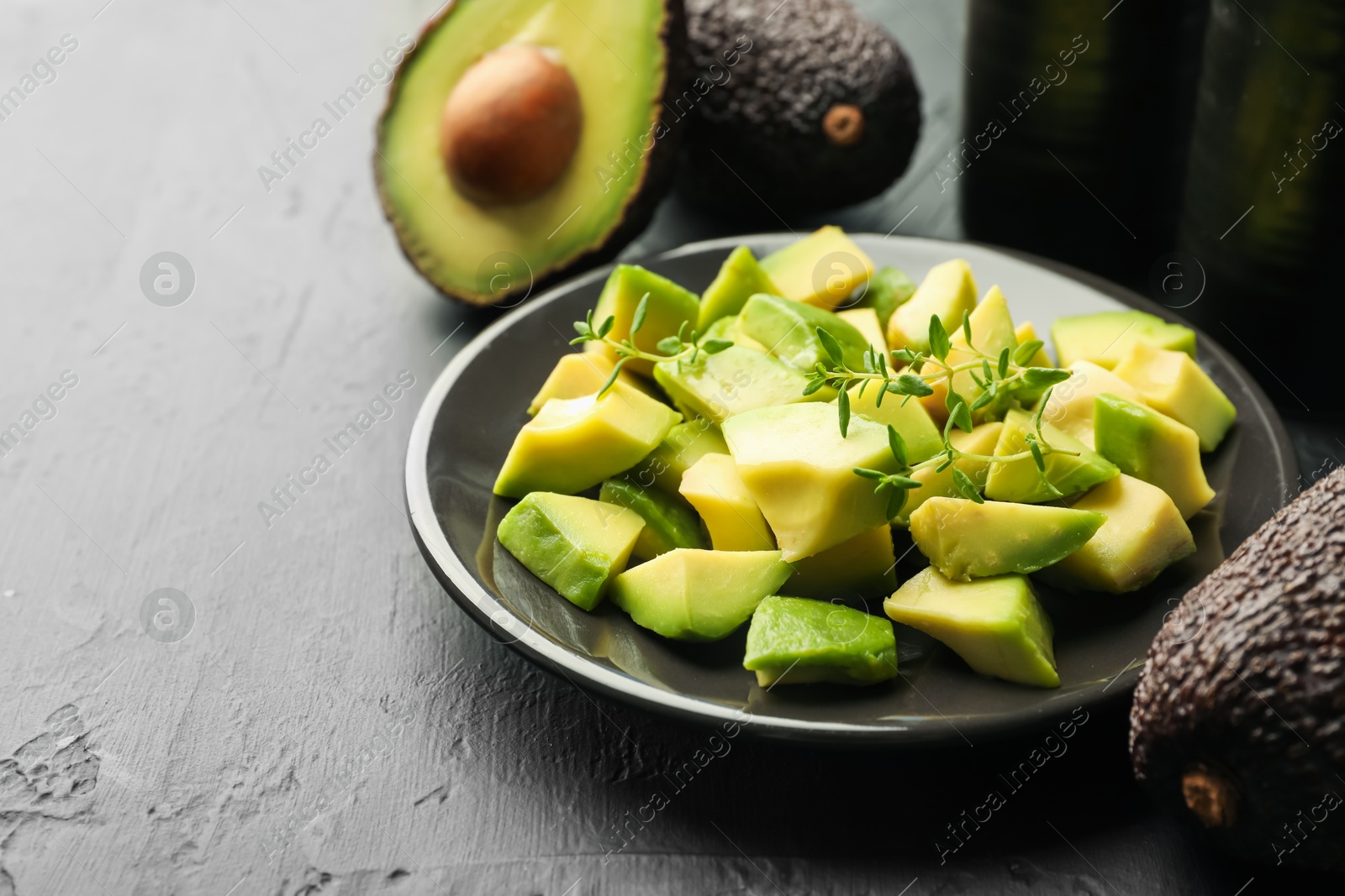 Tasty cut avocados and thyme on black table, closeup. Space for text Photo of Tasty cut avocados and thyme on black table, closeup. Space for text