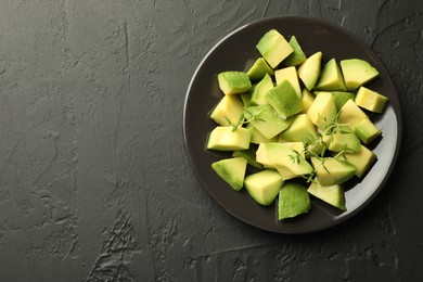 Photo of Tasty cut avocados and thyme on black table, top view. Space for text