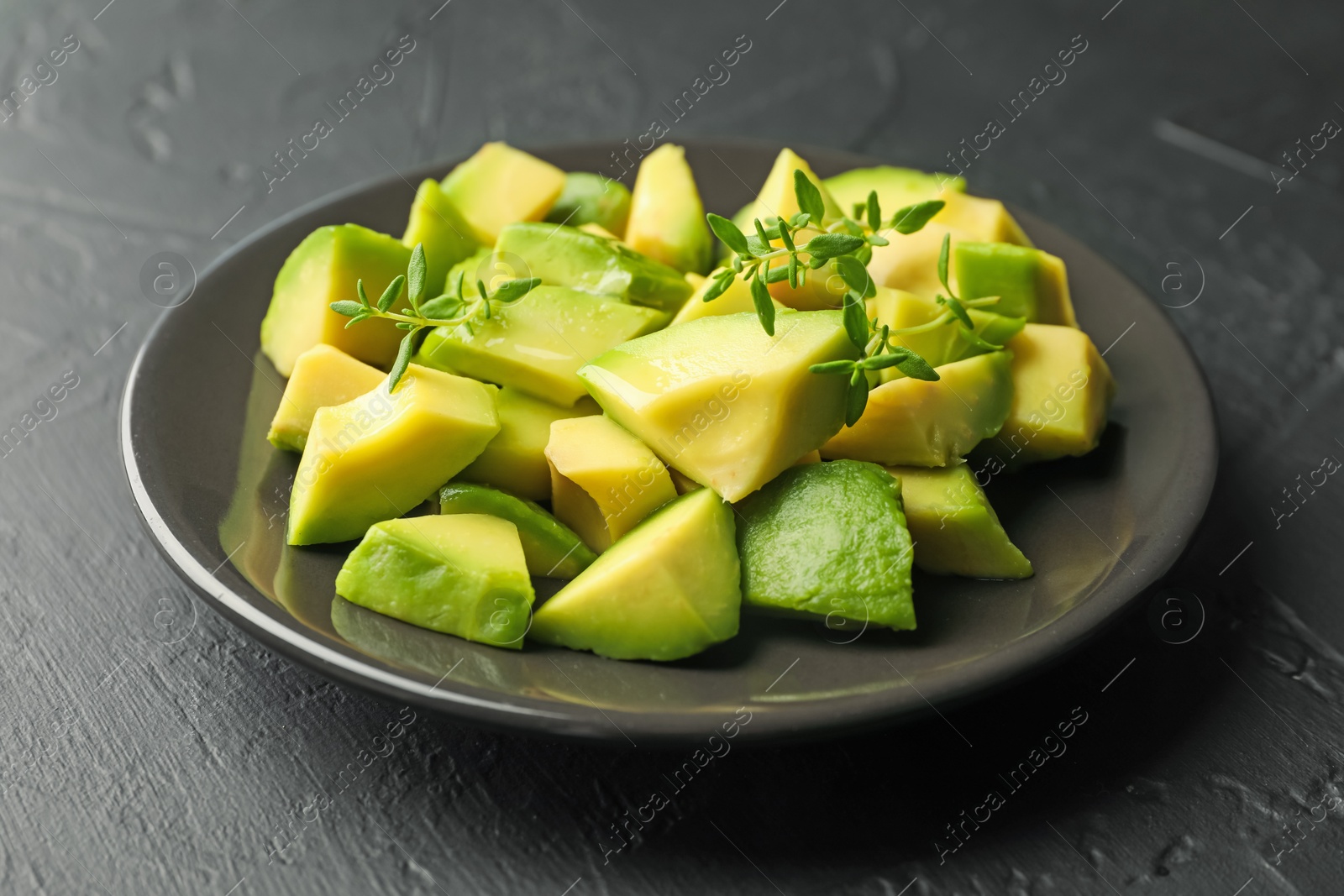 Tasty cut avocados and thyme on black table, closeup Photo of Tasty cut avocados and thyme on black table, closeup