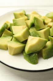 Photo of Tasty cut avocados on white wooden table, closeup