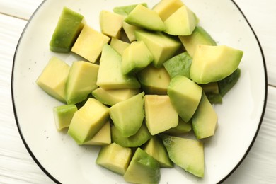 Photo of Tasty cut avocados on white wooden table, top view