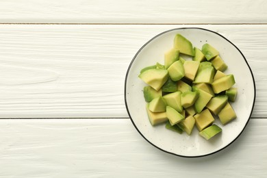 Photo of Tasty cut avocados on white wooden table, top view. Space for text