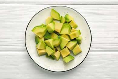 Photo of Tasty cut avocados on white wooden table, top view