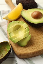 Photo of Tasty cut avocados and lemon on white wooden table, closeup