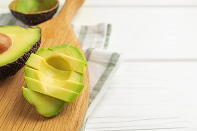 Photo of Tasty cut avocados on white wooden table, closeup. Space for text