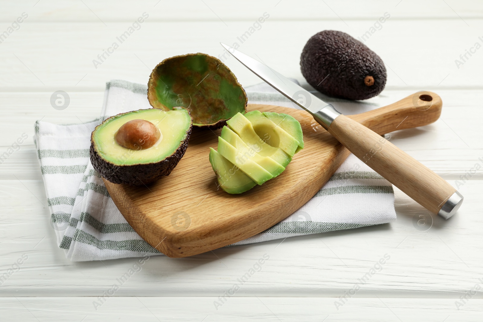 Tasty cut avocados and knife on white wooden table Photo of Tasty cut avocados and knife on white wooden table